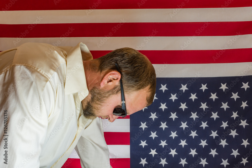 Presidential election disbelief. Man visibly disappointed in front of an upside down American flag.