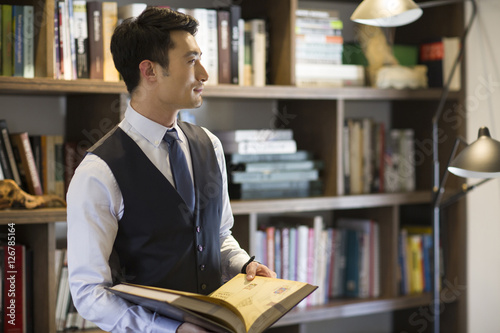 Young businessman reading book in his study