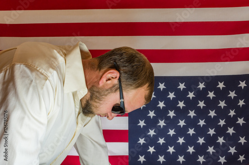 Obraz na płótnie Presidential election disbelief. Man visibly disappointed in front of an upside down American flag. w salonie