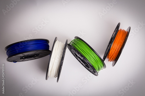 Billede på lærred Bird view of blue, white, green and orange 3D printer filament spools loosely ar