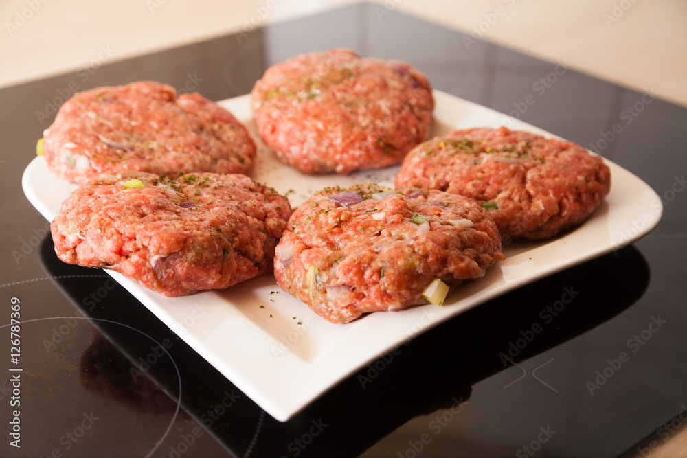 raw meat burger lies on a plate