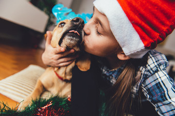 Girl with santa hat kissing dog