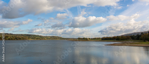 Fototapeta Naklejka Na Ścianę i Meble -  Panorama of Blagdon Lake, Somerset, UK. Resevoir at the edge of the Mendip Hills in England, with flock of birds under blue sky with clouds