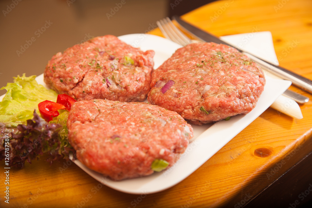 raw meat burger lies on a board