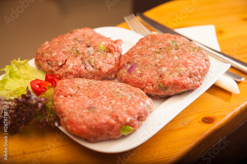 raw meat burger lies on a board