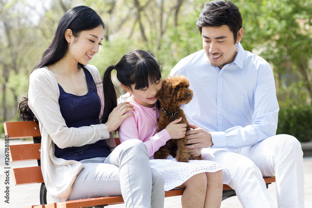 Happy young family playing with their pet dog outdoors Happy young family playing with their pet dog outdoors