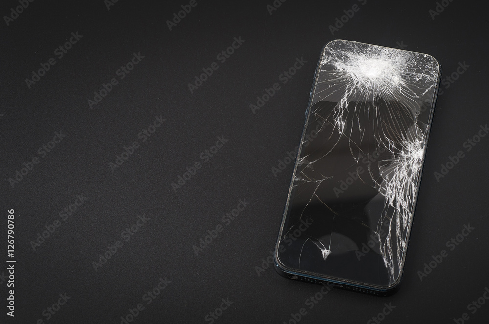 Smartphone with broken screen on dark background Smartphone with broken screen on dark background