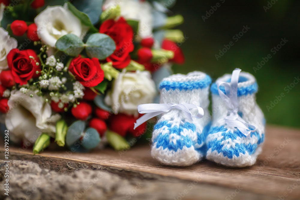 Wedding bouquet of roses and baby booties on wooden background