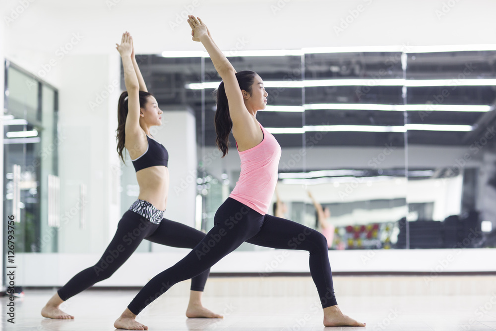 Young women practicing yoga at gym