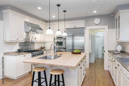 Amazing Luxury Kitchen Interior in white with wooden floor and kitchen island. photo
