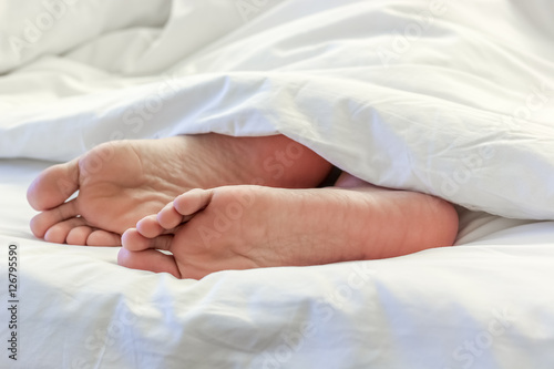 Feet of sleeping woman in white bed room