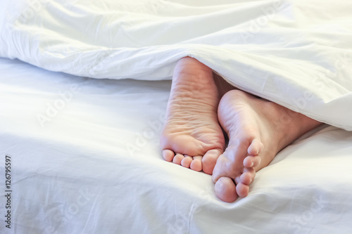 Feet of sleeping woman in white bed room