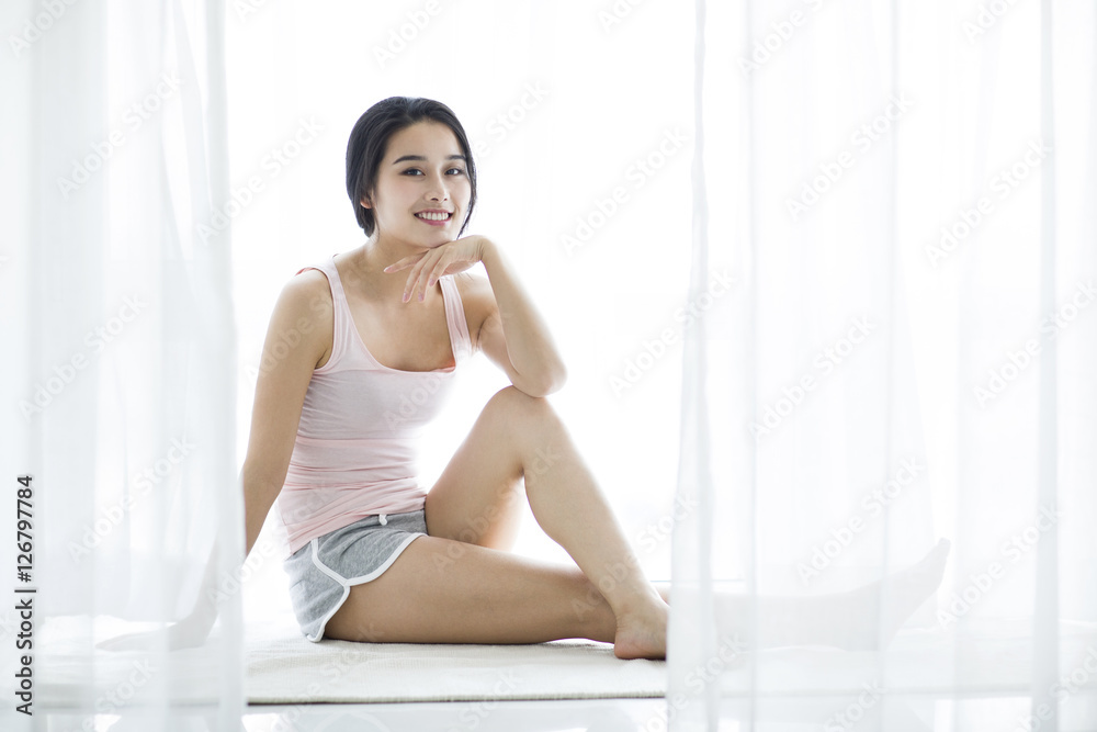 Happy young woman sitting on window sill Happy young woman sitting on window sill