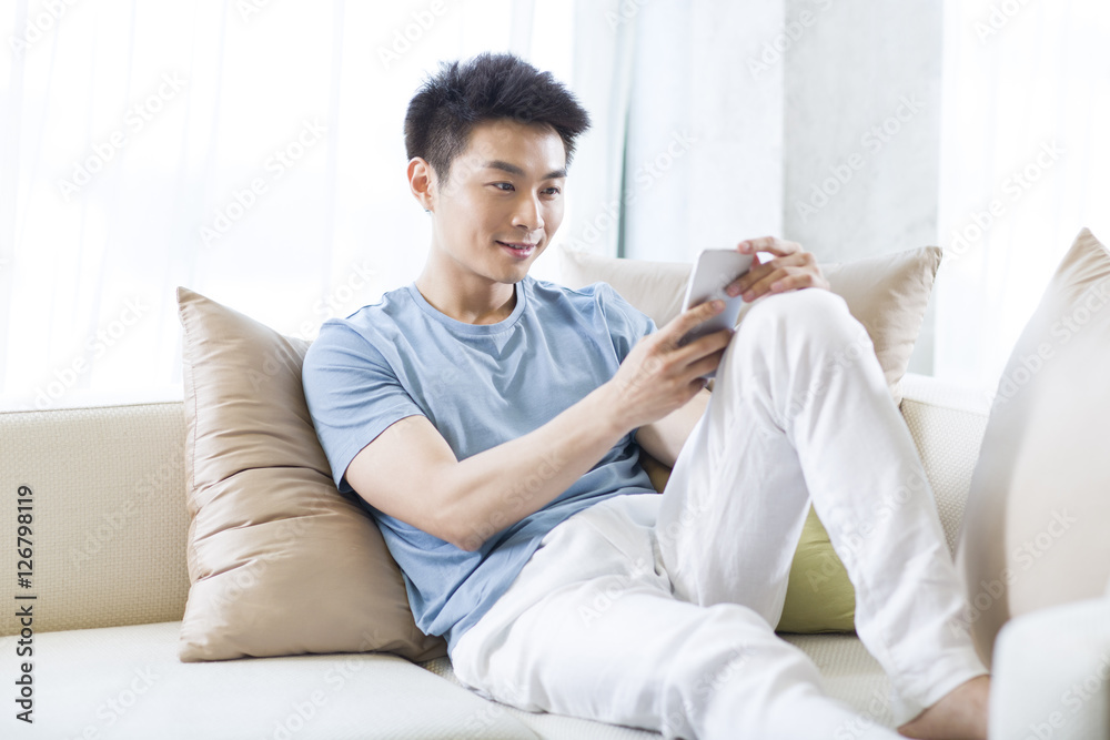 Young man using smart phone on the sofa Young man using smart phone on the sofa