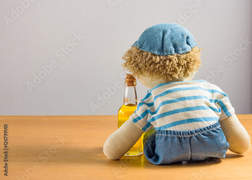 Foto A doll sitting with a bottle of drink