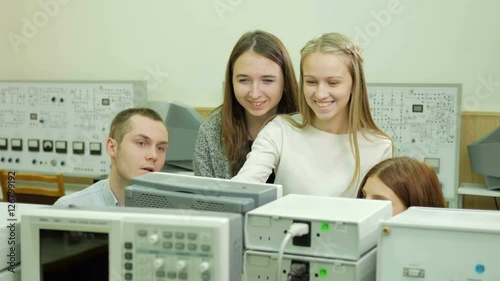 Young student engineers team work in the University of the electrical laboratory. They counsel and test oscilloscope voltmeter readings on the instruments. Future scientists