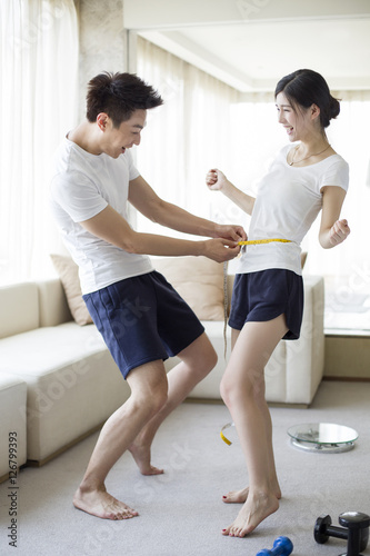 Young man measuring the waist of his wife