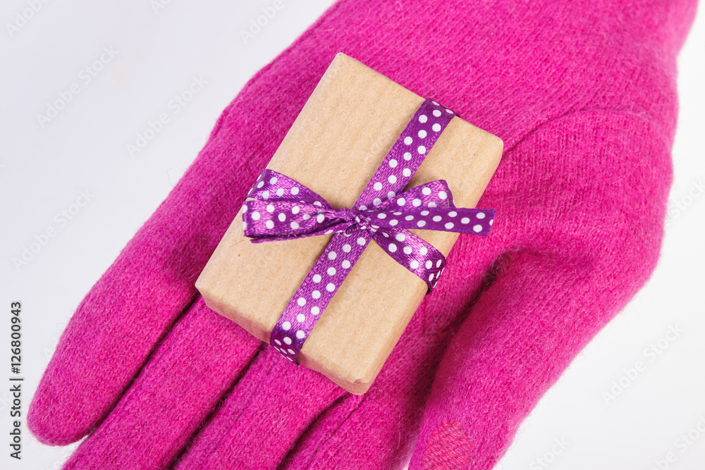 Hand of woman in gloves with gift for Christmas or other celebration