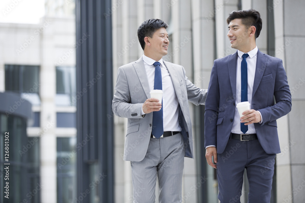 Confident businessmen talking and walking outdoors Confident businessmen talking and walking outdoors