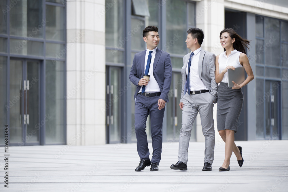 Business people talking while walking outdoors Business people talking while walking outdoors