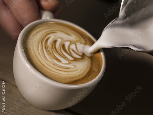 hand of barista making cappuccino coffee pouring milk making lat