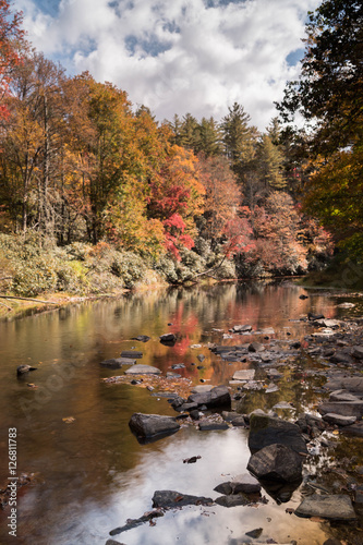 a river with rocks in the foreground and fall foliage in the background in the Appalachians of western North Carolina just off of the Blue Ridge Parkway