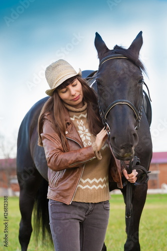 Woman and horse, beige pullover, leather jacket, jeans, hat, cl