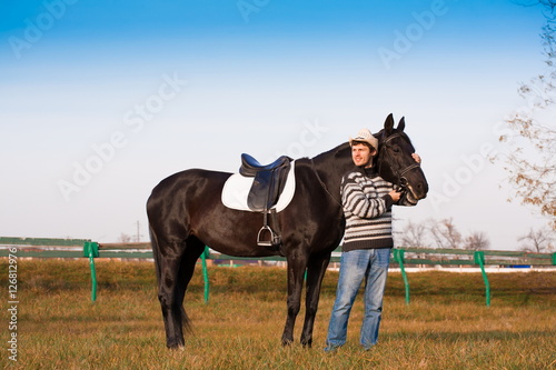 Man nearby horse, striped pullover, blue jeans, hat, landscape © erainbow