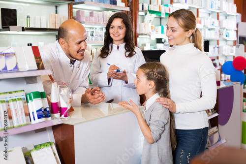 Two pharmacists helping customers