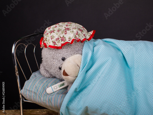 Teddy bear in a bed with a grippe photo