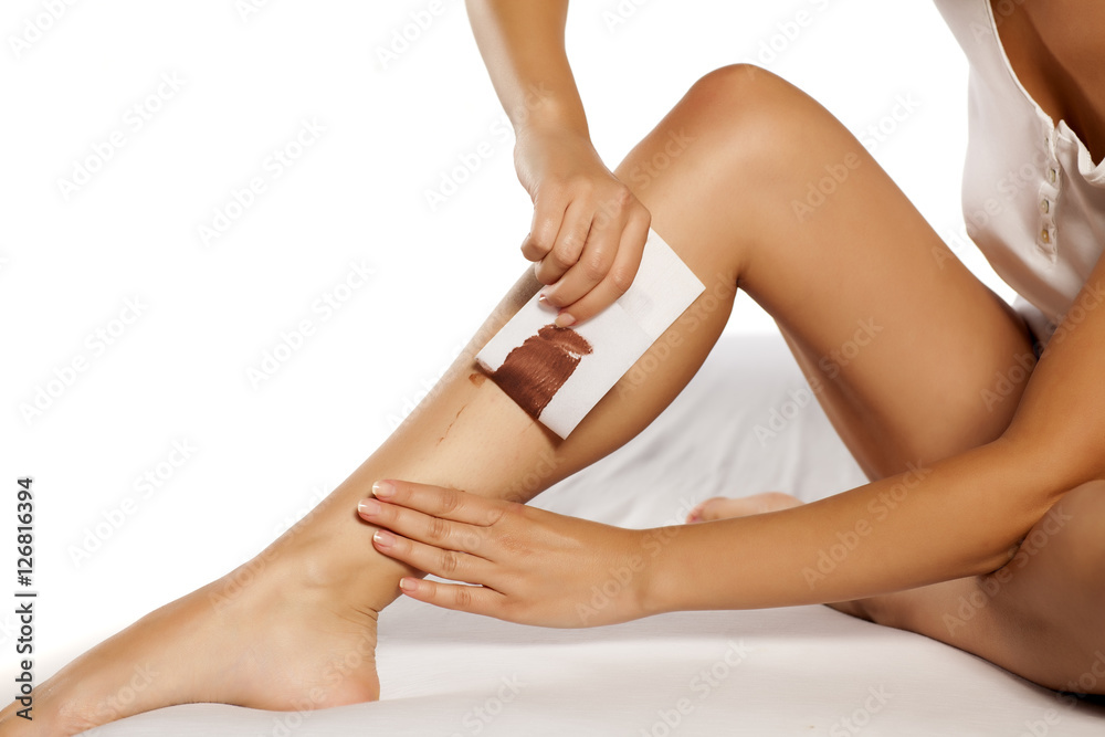 woman waxing her legs using tape and wax for depilation