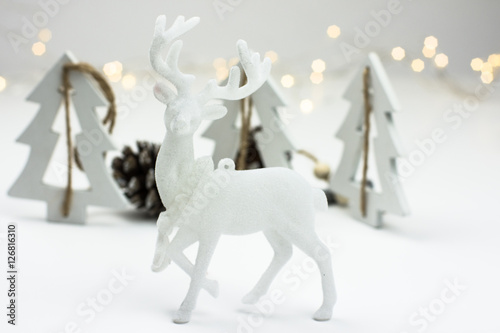 White Christmas decoration in scandinavian style with reindeer, wood fir treeas and pine cones, bokeh lights in the background photo