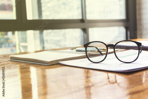 Close up of eye glasses on work desk with chart and laptop at business workplace