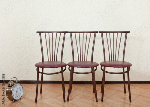 Three of the same chair against the wall next to the alarm