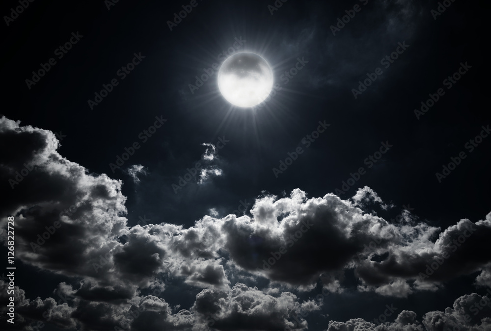 Obraz premium Dramatic photo illustration of a nighttime sky with brightly lit clouds and large. Beautiful starry night sky with clouds and bright full moon or super moon.