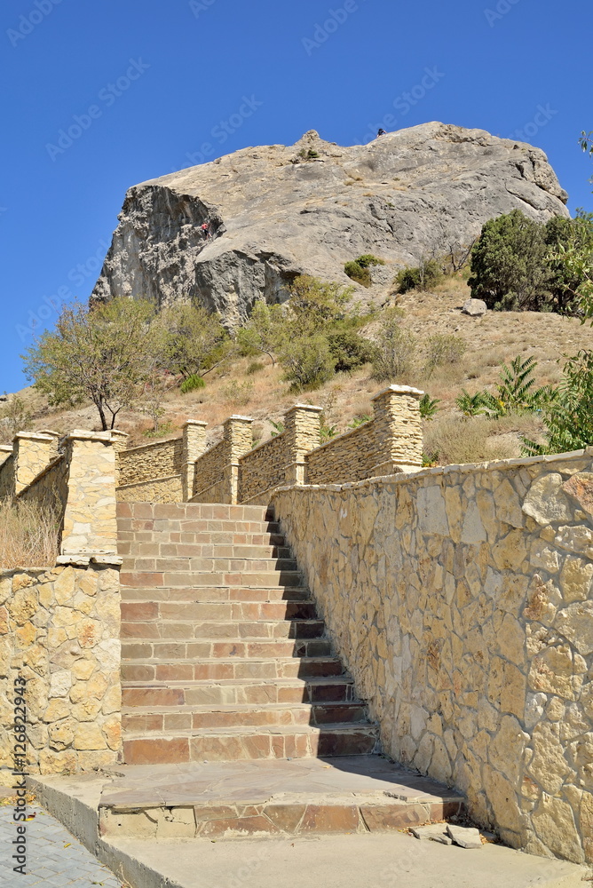 A stone staircase into the mountain lit by the sun
