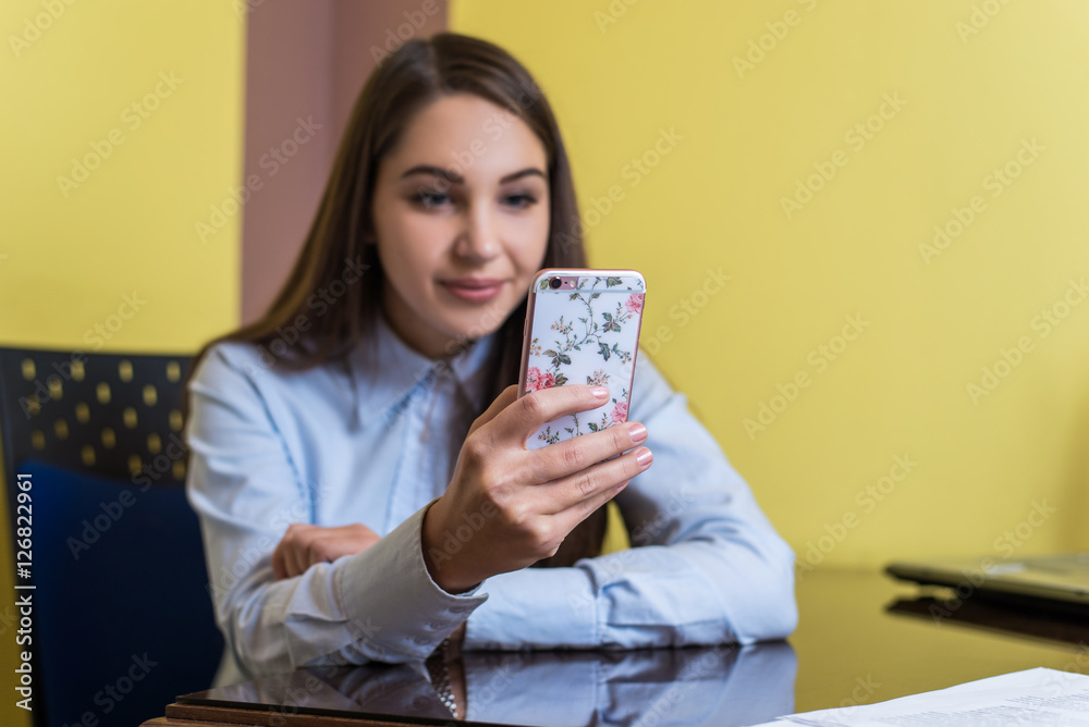 Cute young woman chatting with friend or shopping online with smartphone. Beautiful phone cover with pink flowers. Cute young woman chatting with friend or shopping online with smartphone. Beautiful phone cover with pink flowers.