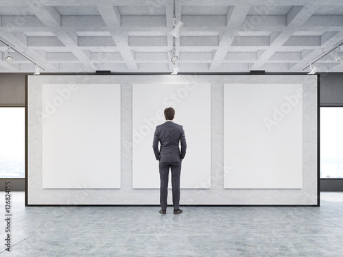 Man looking at three posters in a gallery