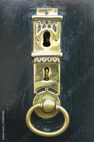 A dark green painted wooden door with a beautifully forged golden key hole