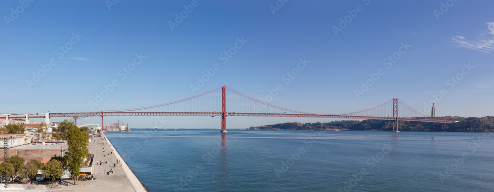 Obraz premium Lisbon, Portugal - October 31, 2016: The 25 de Abril bridge spanning over the Tagus River seen from the Belem District. On the right it’s seen the famous the Cristo-Rei Sanctuary.
