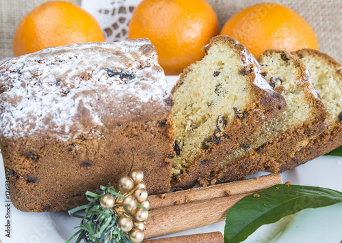 Christmas composition with a sliced cake with raisins and glass of tea on a white dish photo