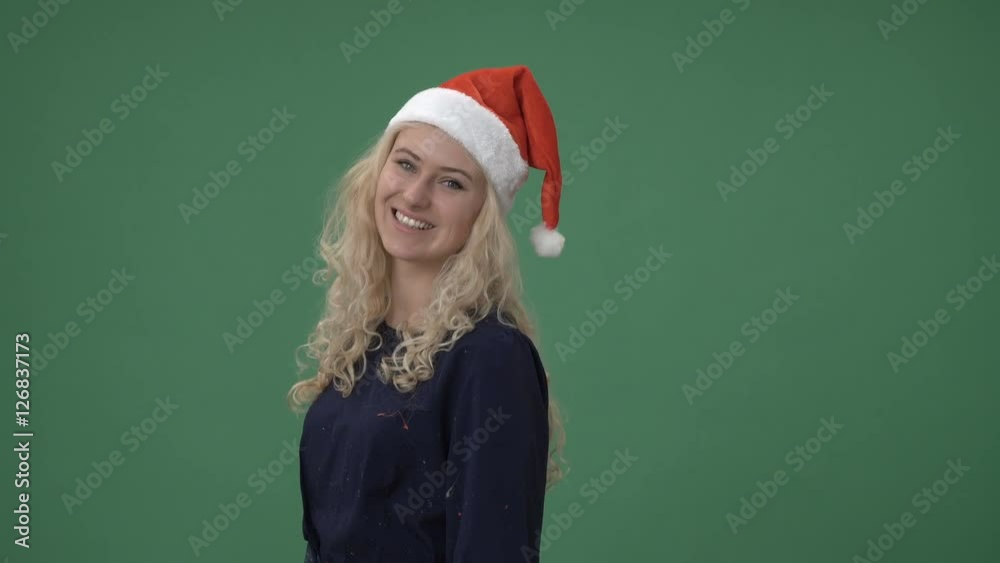 Young blonde woman in a red christmas cap turning and smiling, chroma key green screen Young blonde woman in a red christmas cap turning and smiling, chroma key green screen