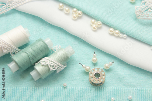 the thread, the beads, the lace are on the turquoise fabric