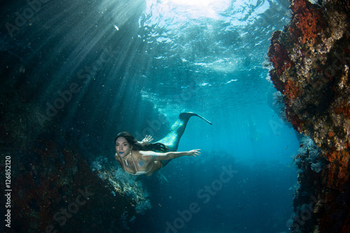 Mermaid swimming underwater in the deep blue sea
