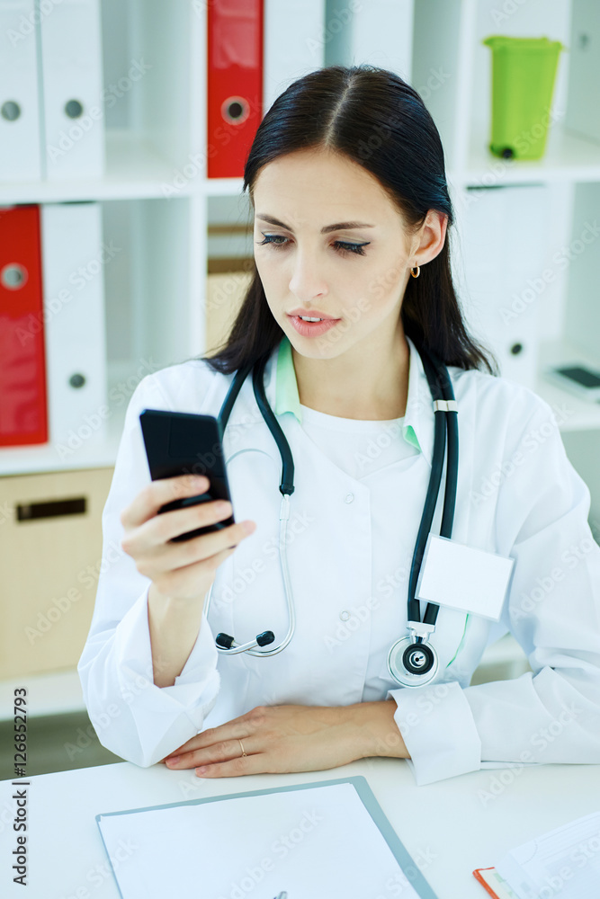 Portrait of a beautiful medical doctor looking at mobile phone. Portrait of a beautiful medical doctor looking at mobile phone.