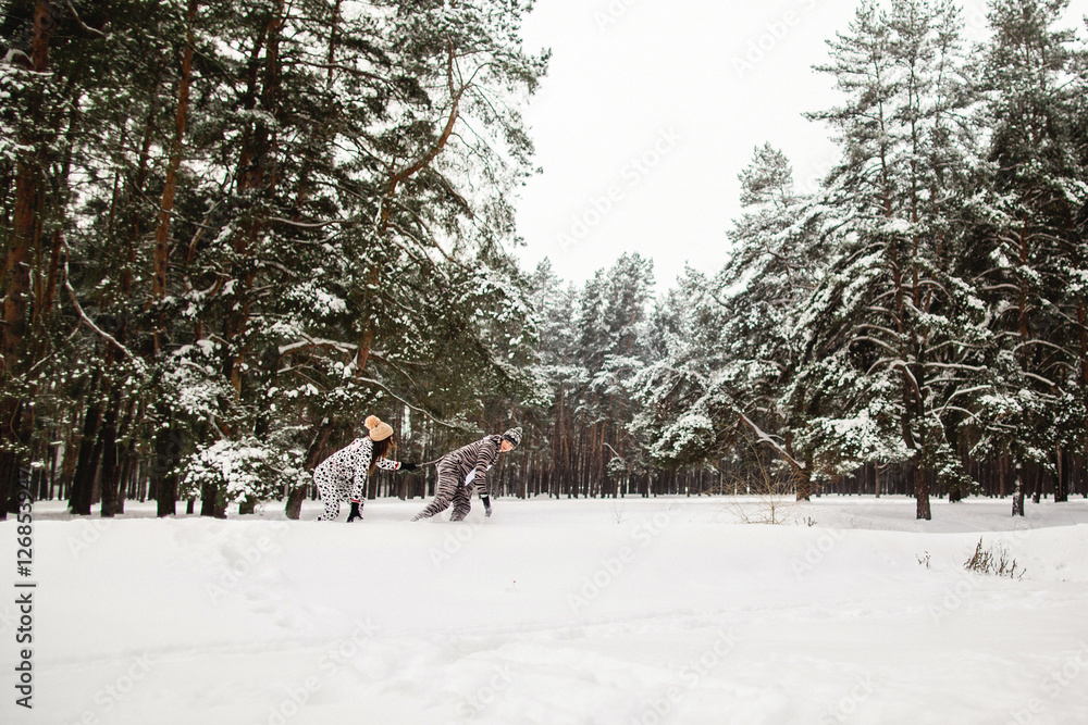 Winter concept, couple in animals costumes running in the snowy winter pine forest 