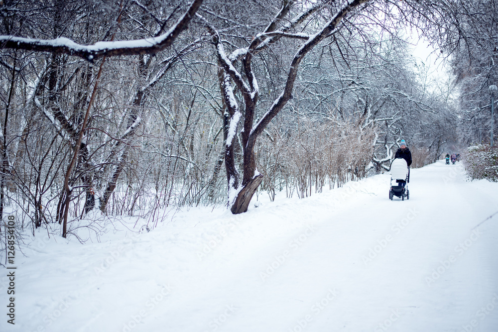 Woman with pram walking in winter Woman with pram walking in winter