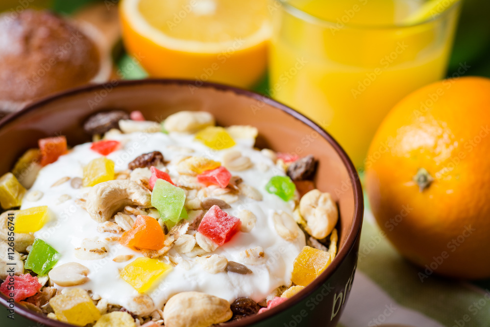 Healthy breakfast with yogurt, muesli and candied fruit in ceramic bowl on green wooden background Healthy breakfast with yogurt, muesli and candied fruit in ceramic bowl on green wooden background