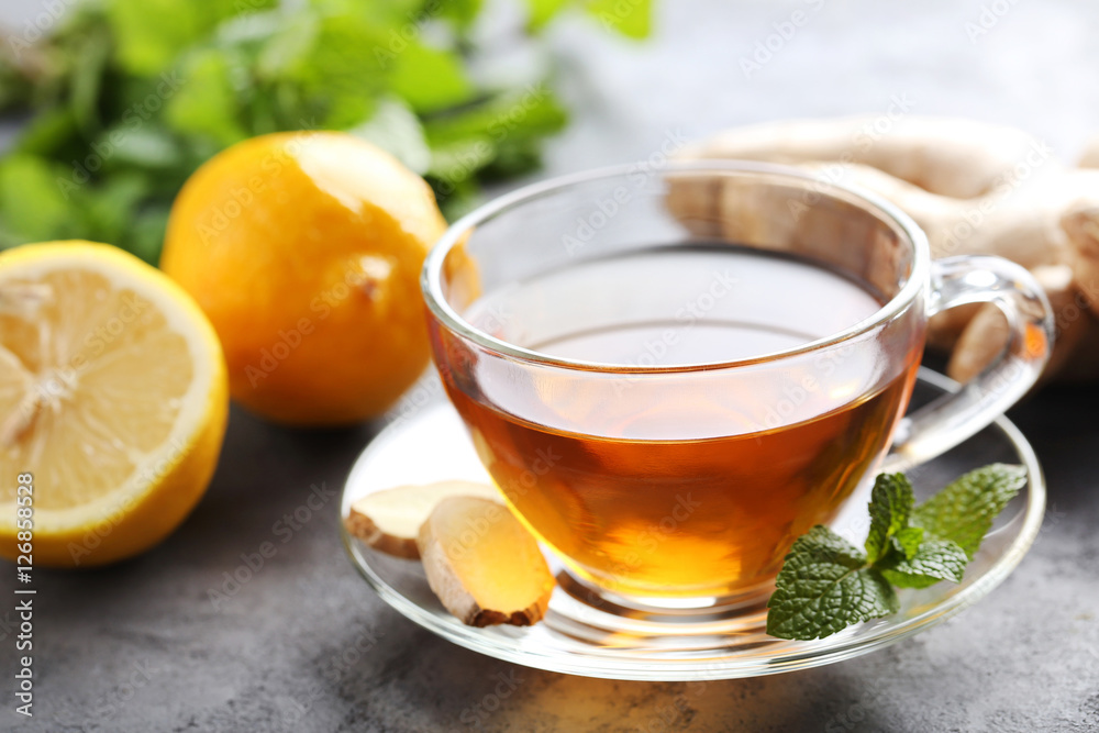 Cup of tea with ginger root and lemon on grey wooden table Cup of tea with ginger root and lemon on grey wooden table