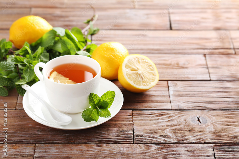 Cup of tea with mint and lemon on brown wooden table Cup of tea with mint and lemon on brown wooden table